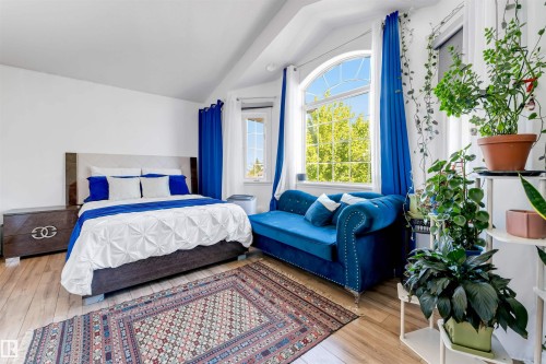 Bedroom with wood-finish flooring, a vaulted ceiling, and an arched window - 7920 7 Avenue, Edmonton, AB 
