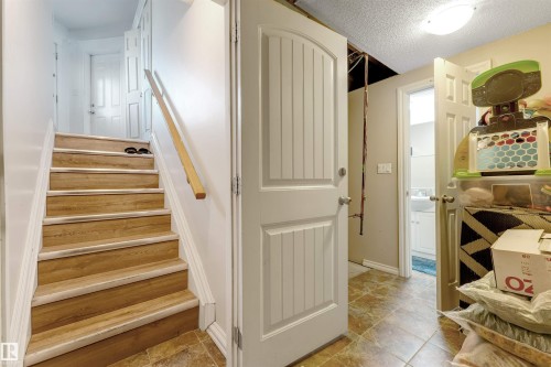 Wood-finish staircase with white risers and a light wood handrail - 7920 7 Avenue, Edmonton, AB 