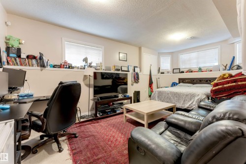 Open-concept living area featuring a neutral color palette, recessed lighting, and multiple windows providing natural illumination - 7920 7 Avenue, Edmonton, AB 