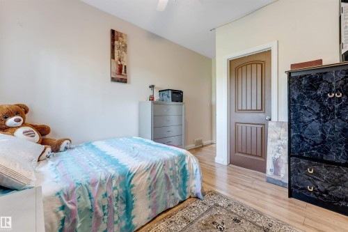 Wood-finish flooring throughout, featuring a five-panel interior door with a white trim frame and a ceiling fan - 7920 7 Avenue, Edmonton, AB 