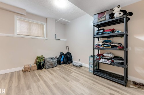 Room featuring wood-finish flooring, neutral wall paint, and a textured ceiling - 7920 7 Avenue, Edmonton, AB 