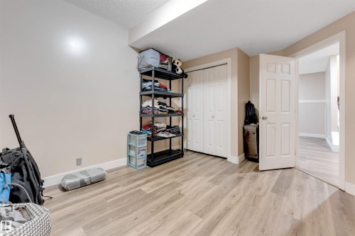 Neutral toned room featuring wood-finish flooring, white baseboards, and a white six-panel door - 7920 7 Avenue, Edmonton, AB 