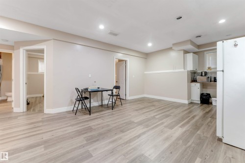 Spacious room featuring light wood-finish flooring, recessed lighting, and neutral wall tones - 7920 7 Avenue, Edmonton, AB 