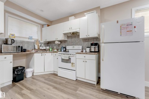 Kitchen featuring white cabinetry, stone-look countertops, and a tile backsplash - 7920 7 Avenue, Edmonton, AB 
