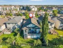 Backyard featuring a multi-level deck, white railings, and a lower-level concrete patio - 7920 7 Avenue, Edmonton, AB 