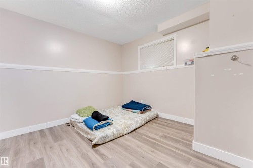 Light wood-finish flooring complements neutral wall tones and white baseboards - 7920 7 Avenue, Edmonton, AB 