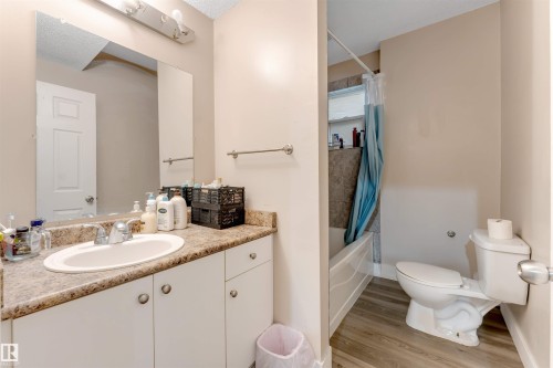 Bathroom featuring a single vanity with an integrated sink, patterned countertop, and white cabinetry - 7920 7 Avenue, Edmonton, AB 