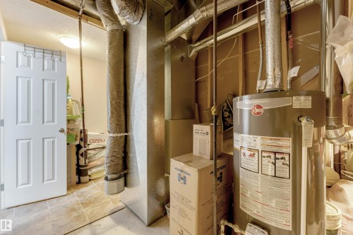 Utility area featuring a water heater, exposed ductwork, and electrical conduit - 7920 7 Avenue, Edmonton, AB 