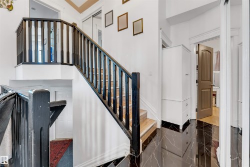 Staircase with dark wood balusters and handrails, light wood treads, and white risers - 7920 7 Avenue, Edmonton, AB 