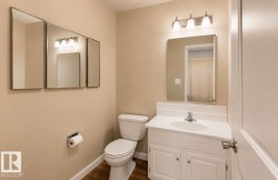 Bathroom featuring a white vanity with integrated sink, chrome faucet, and overhead three-bulb light fixture - 