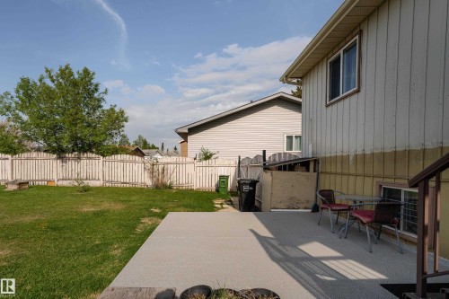 Expansive backyard featuring a large concrete patio, a manicured lawn, a white picket fence, and mature foliage - 4620 37A Avenue, Edmonton, AB - Outdoor With Exterior