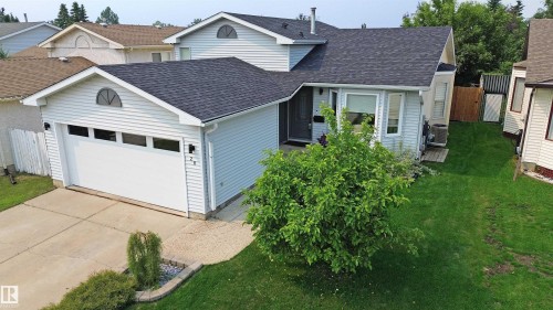 Light blue vinyl siding exterior with an attached garage, featuring a white garage door with upper window panels - 20 Aberdeen Way, Stony Plain, AB 