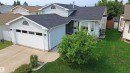 Light blue vinyl siding exterior with an attached garage, featuring a white garage door with upper window panels - 20 Aberdeen Way, Stony Plain, AB 