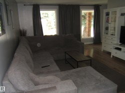 Living area featuring wood-finish flooring, light grey wall paint, and two windows with drapery rods - 