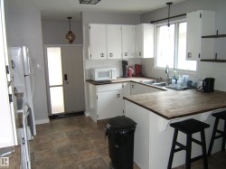 Kitchen featuring white cabinetry, light wood-finish countertops, and a white subway tile backsplash - 