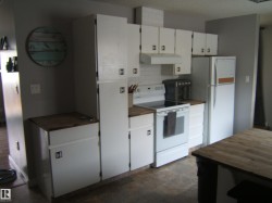 Kitchen featuring white cabinetry, wood-finish countertops, white subway tile backsplash, and a white electric range - 