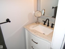 White vanity with curved drawers, a light-toned countertop, and an undermount sink - 