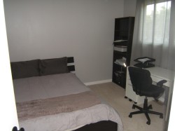 Neutral-toned bedroom featuring wall-to-wall carpeting and a window with sheer drapes - 