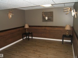 Room featuring wood-finish flooring, wood-paneled wainscoting, and neutral-toned painted walls - 