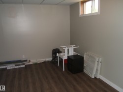 Versatile room featuring wood-finish flooring, neutral-toned walls, and a drop ceiling - 