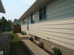 Cream-colored siding exterior featuring multiple windows and a white entry door - 