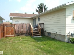 Rear exterior featuring a wood-plank deck with railing, stairs, and lattice skirting - 