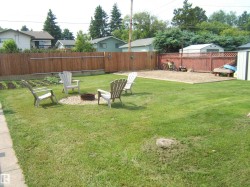 Expansive green lawn area featuring a gravel fire pit surround - 
