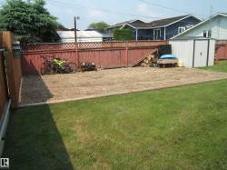 Expansive backyard featuring a manicured lawn, a gravel-covered area, and a wood privacy fence - 