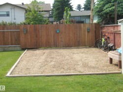 Fenced backyard featuring a gravel pad and a manicured lawn - 