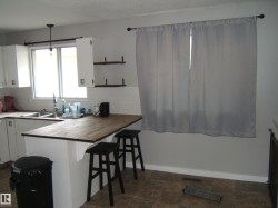 Kitchen with white cabinetry, wood-finish countertops, and a white subway tile backsplash - 