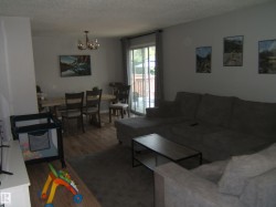 Open concept living and dining area featuring wood-finish flooring, a sliding glass door to an outdoor deck, and neutral wall tones - 