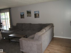 Living area featuring light gray wall paint, wood-finish flooring, and a sliding glass door providing exterior access - 