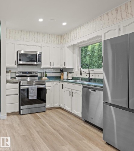 Kitchen with wood-finish flooring, white cabinetry, recessed lighting, and stainless steel appliances - 8822 161 Street, Edmonton, AB 