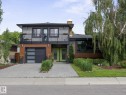 Contemporary two-story exterior featuring a balcony, wood-look siding, a modern garage door with frosted panels, and a vibrant green double entry door - 8822 161 Street, Edmonton, AB 