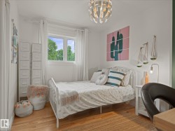Bright room featuring hardwood flooring, a large window, white walls, a contemporary ceiling light fixture, and a white side table - 