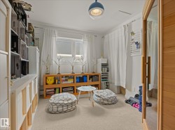 Versatile room featuring light-colored carpeting and a window with white drapes - 