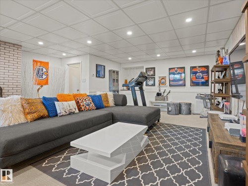 Finished lower level with recessed lighting, light-toned carpeting, and a white brick-finish wall accent - 8822 161 Street, Edmonton, AB 