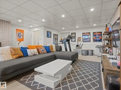 Finished lower level with recessed lighting, light-toned carpeting, and a white brick-finish wall accent - 
