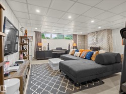 Expansive recreation room featuring a white brick fireplace, recessed lighting, and a drop ceiling - 