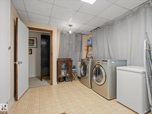 Dedicated laundry area featuring patterned tile flooring, a drop ceiling, and a ceiling-mounted light fixture - 8822 161 Street, Edmonton, AB 