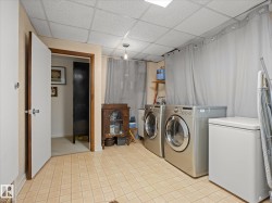 Dedicated laundry area featuring patterned tile flooring, a drop ceiling, and a ceiling-mounted light fixture - 