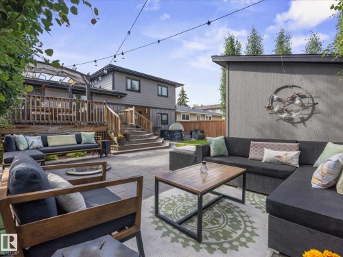 Expansive stone patio with outdoor lighting, providing access to a multi-level wood deck - 8822 161 Street, Edmonton, AB 