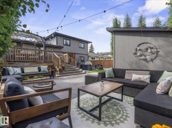 Expansive stone patio with outdoor lighting, providing access to a multi-level wood deck - 