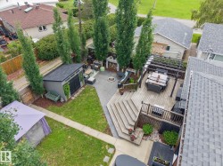 Expansive backyard featuring a multi-level wood deck with pergola, paver patio, mature trees, and a detached storage shed - 