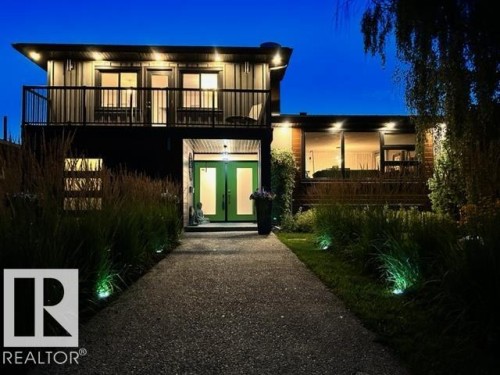 Modern architecture featuring a prominent balcony with dark railing, a striking green double entry door, and large picture windows - 8822 161 Street, Edmonton, AB 