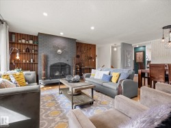 Living area featuring a gray brick fireplace with a hearth, recessed lighting, and wood-finish wall paneling with built-in shelving - 