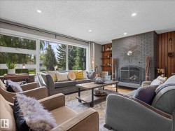 Living area featuring a gray brick fireplace with an arched firebox, wood paneling, built-in shelving, recessed lighting, and large picture windows - 