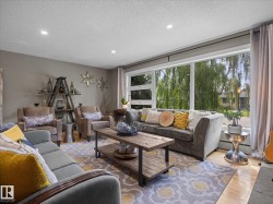 Spacious living area featuring large picture windows, recessed lighting, wood-finish flooring, a decorative area rug, and a rustic wood coffee table - 