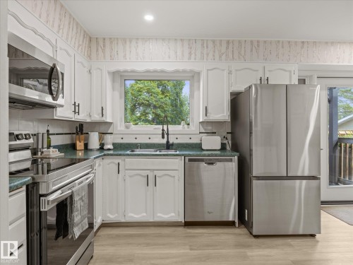 Kitchen featuring white cabinetry with dark hardware, green countertops, and a white subway tile backsplash - 8822 161 Street, Edmonton, AB 