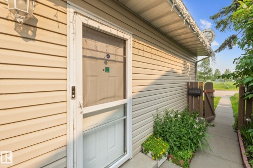 Entryway featuring a white screen door, light-toned siding, and an overhead exterior light fixture - 18126 98 Avenue, Edmonton, AB 